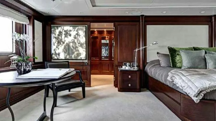 Guest cabin aboard M/Y Azteca with made bed and dark wood paneling