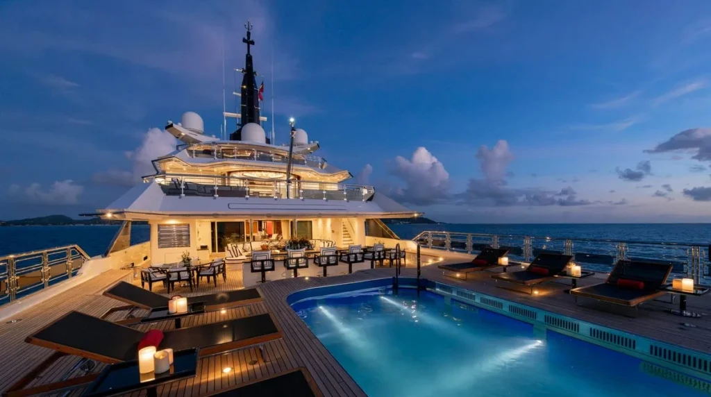 Alfa Nero superyacht aft pool deck lit at night with poolside loungers and candlelight