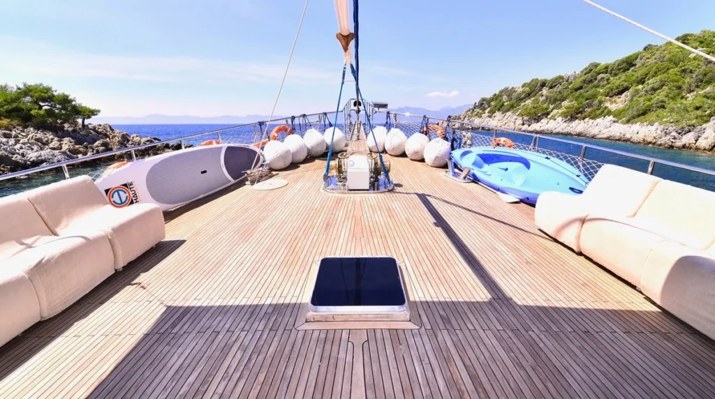 Efe Burak gulet foredeck lounging area with white cushioned seating, paddleboard and kayak water toys