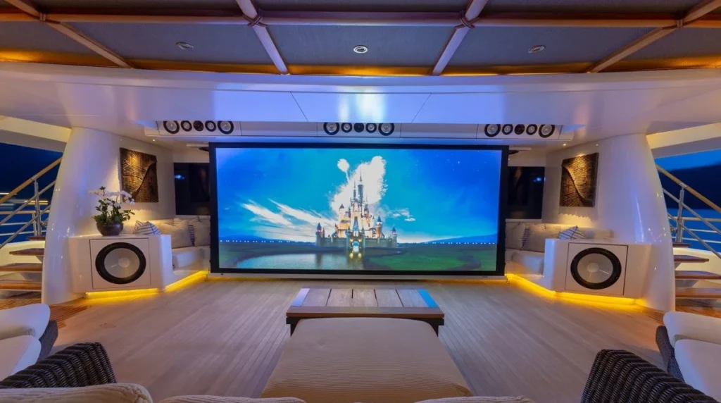 Kogo superyacht outdoor cinema with large screen, surround speakers and aft deck lounge seating at night