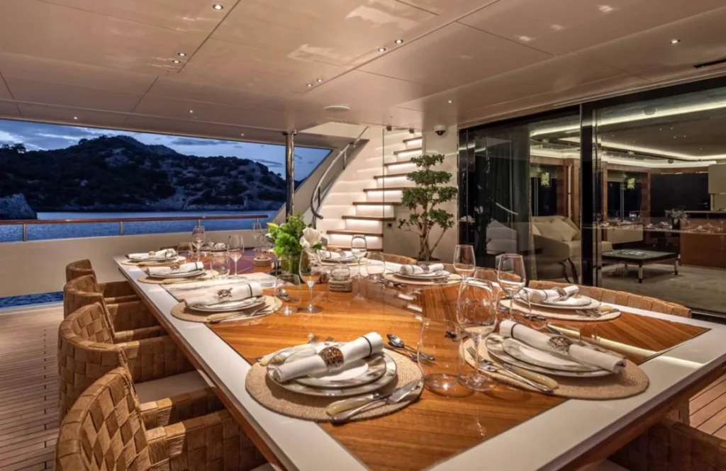 Al fresco dining table set for guests aboard Sunrise yacht at dusk